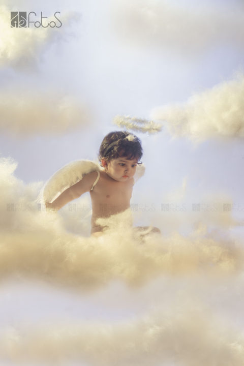 one year pre-birthday photoshoot of cute baby girl in Angel theme, sitting above the clouds in Nagpur.