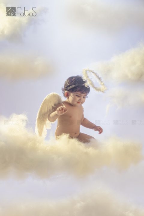 one year pre-birthday photoshoot of cute baby girl in Angel theme, sitting above the clouds in Nagpur.