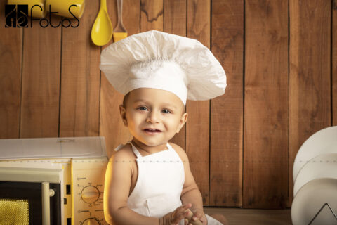 one year pre-birthday photoshoot of baby boy in chef theme, wearing chef hat in Nagpur.