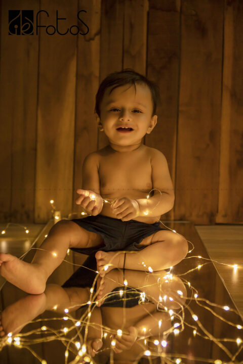 one year pre-birthday photoshoot of baby boy with fairy lights above in Nagpur.