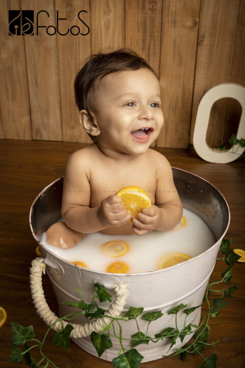 one year pre-birthday photoshoot of baby boy in milk bath theme, with slice of Nagpur oranges in Nagpur.